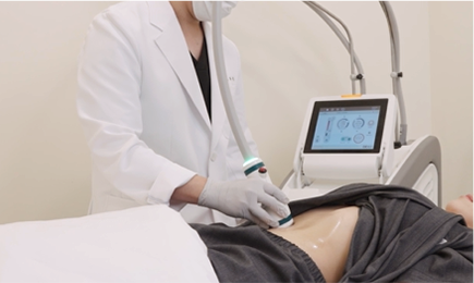 医療スタッフが横になった患者の腹部にボディ機器のハンドピースを当てる様子